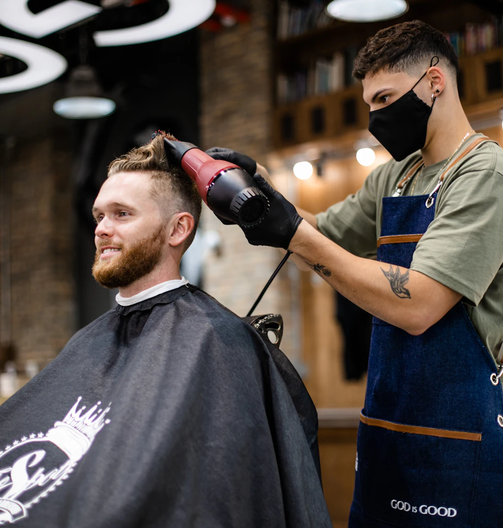 A barber blow-drying a client's freshly cut hair